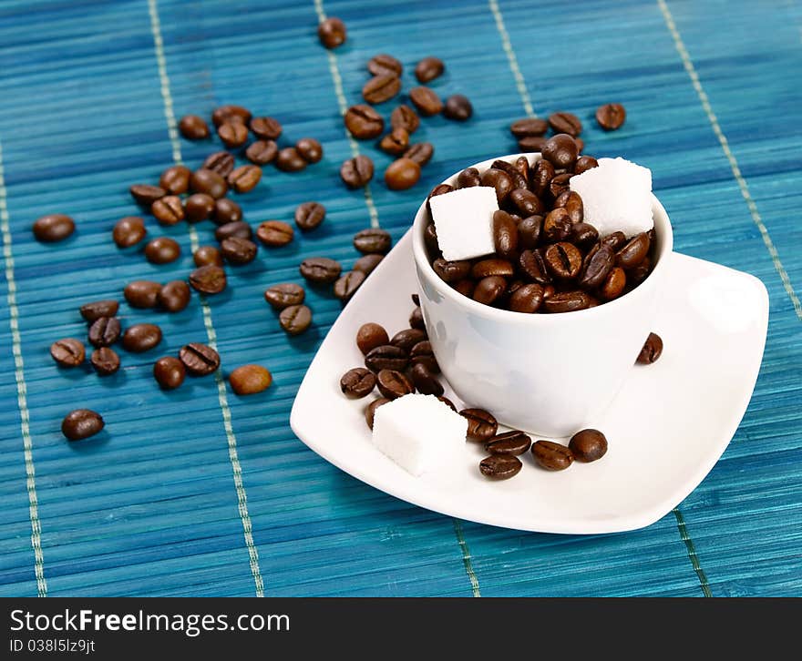 A cup filled with coffee beans and sugar cubes. A cup filled with coffee beans and sugar cubes