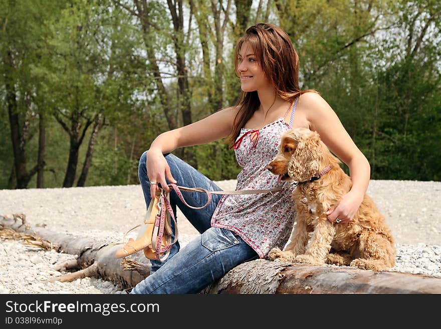 Beautiful brunette young woman sitting on a dead tree with her dog. Beautiful brunette young woman sitting on a dead tree with her dog