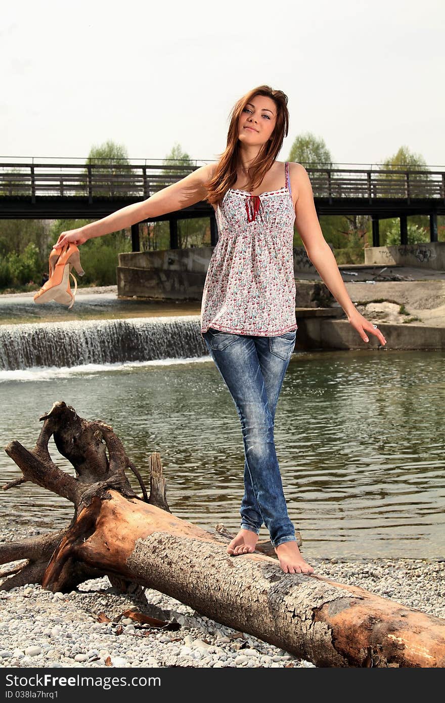 Young brunette woman walking barefoot outside at a river. Young brunette woman walking barefoot outside at a river