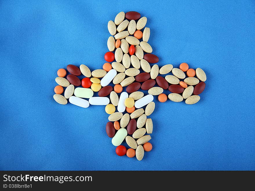 Pills on blue background in form of a cross. Pills on blue background in form of a cross