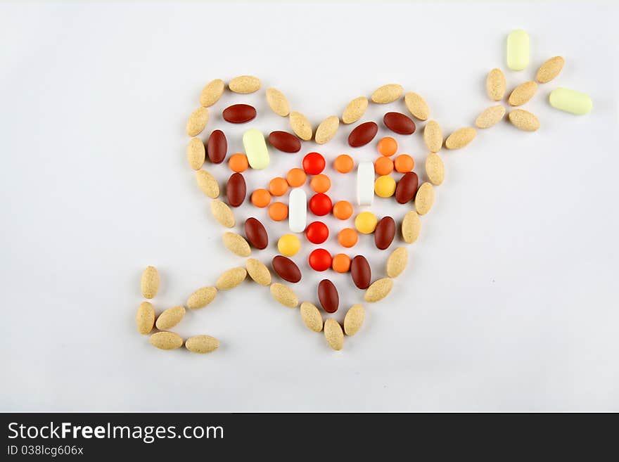 Pills in shape of love heartwitn arrow on white background. Pills in shape of love heartwitn arrow on white background