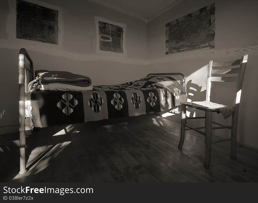 Old wooden house interior, empty room with bed and chair.