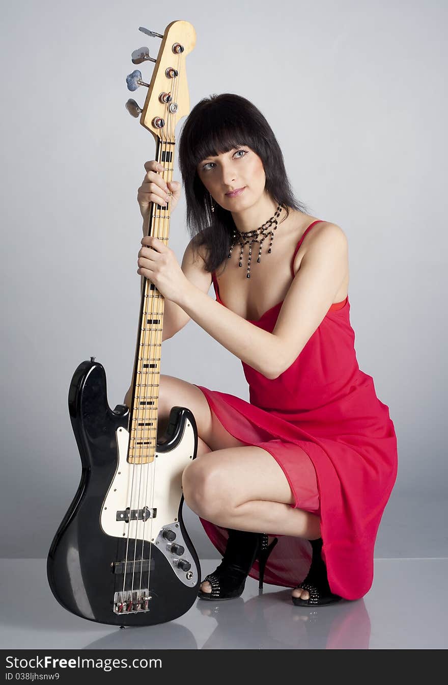 Woman in red dress with guitar in the studio