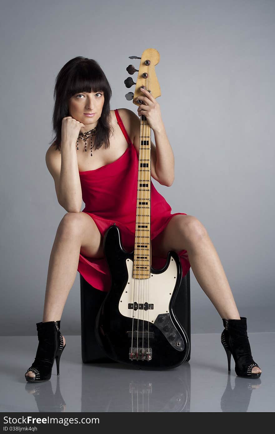 Woman in red dress with guitar in the studio