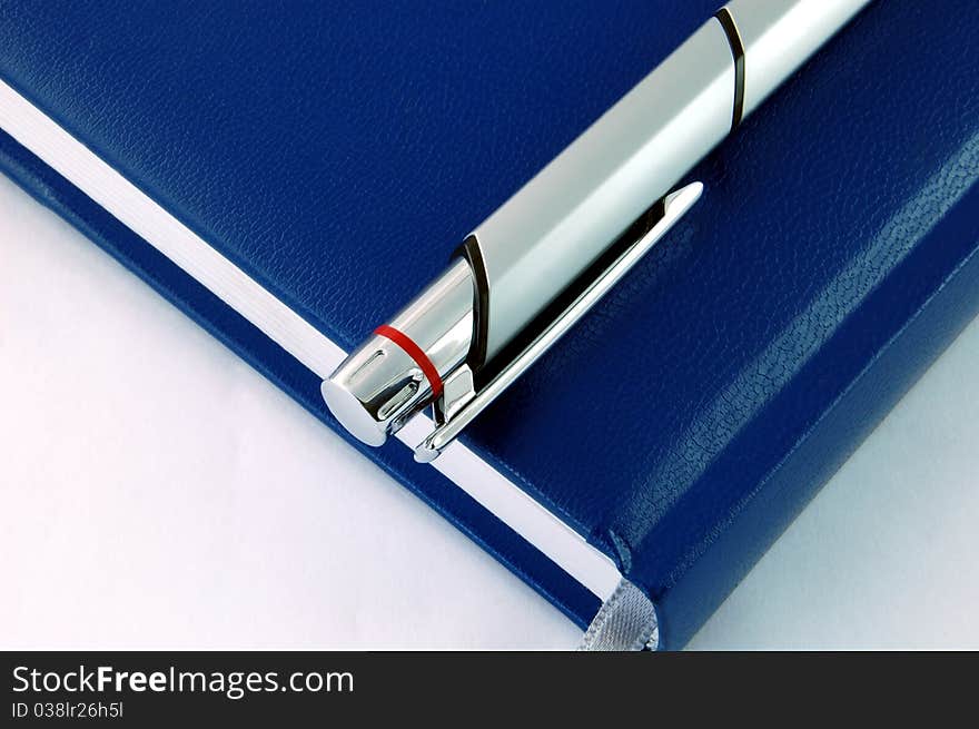 Isolated Blue Agenda With a Silver Shiny Pen. Isolated Blue Agenda With a Silver Shiny Pen