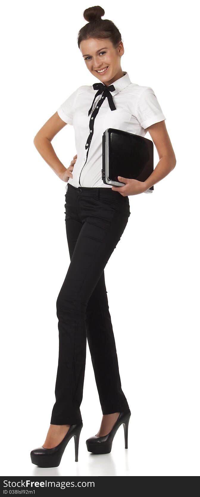 Girl in office attire stands and holds a laptop computer. Isolated image on white background