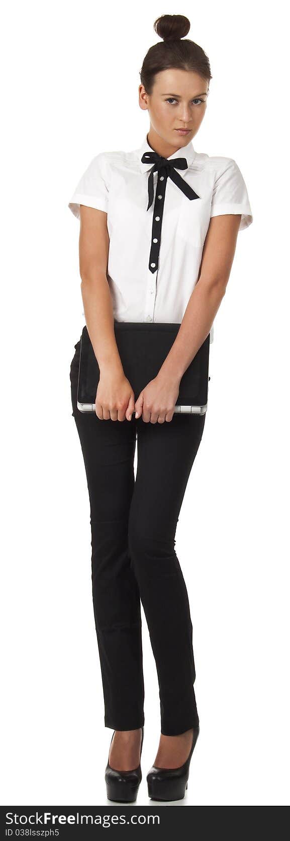 Girl in office attire stands and holds a laptop computer. Isolated image on white background