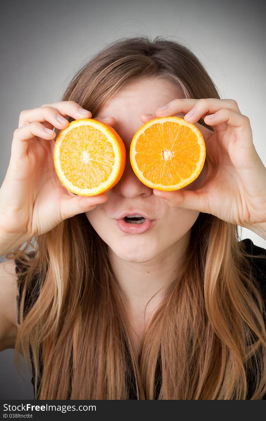 Beautiful blond girl using orange as glasses