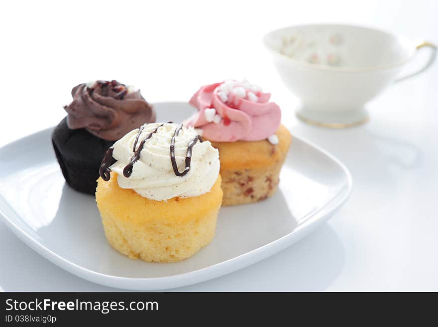 Three colored Muffin on a plate with a cup