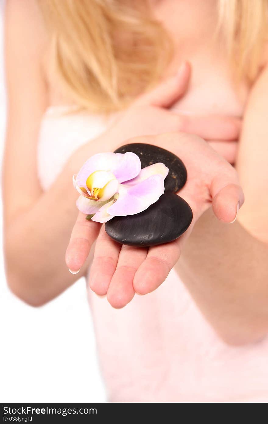 Studio photo of blond girl holding spa stones and orchid blossoms. Studio photo of blond girl holding spa stones and orchid blossoms