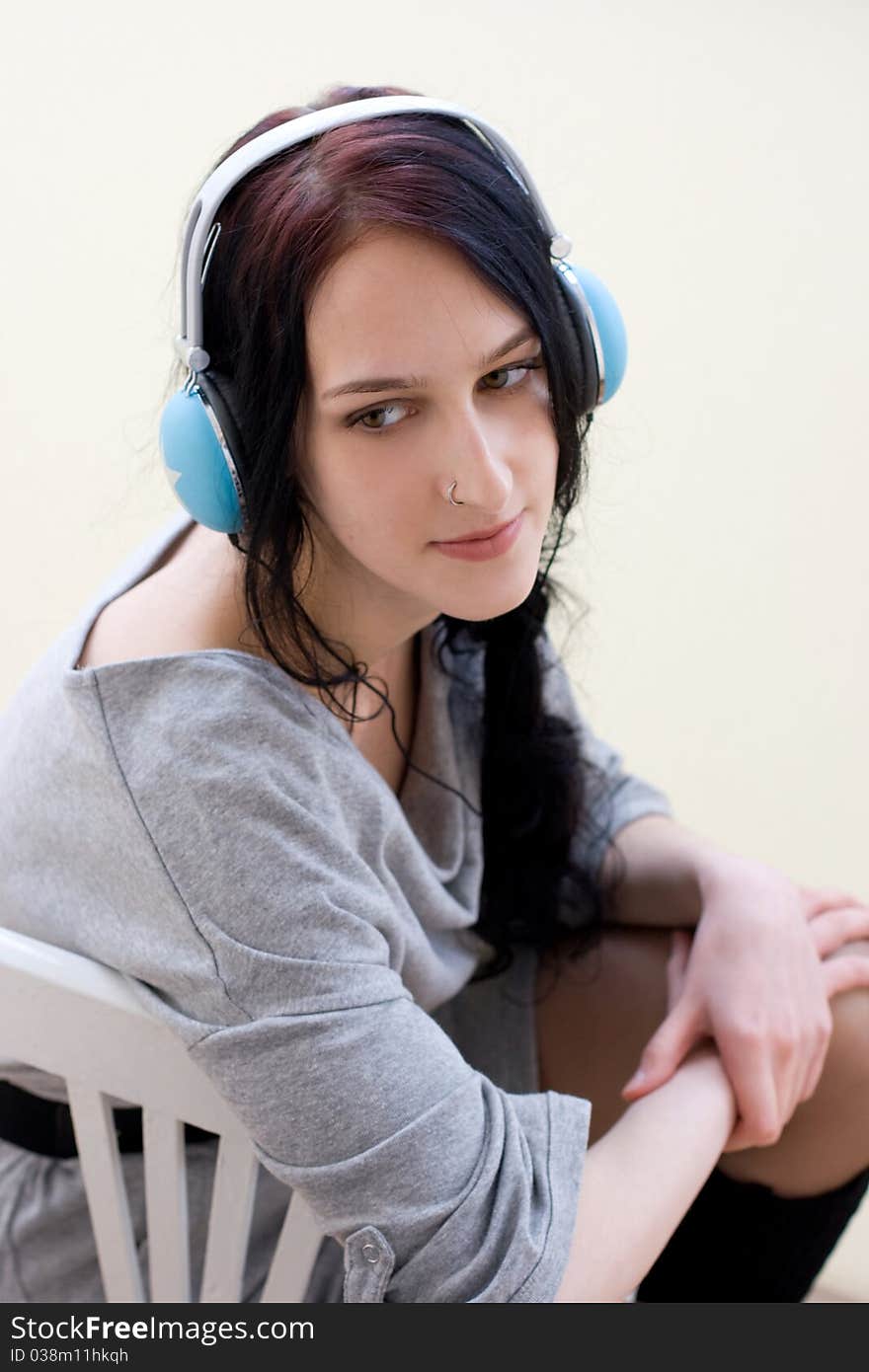 Caucasian dark haired woman with earphones on the chair