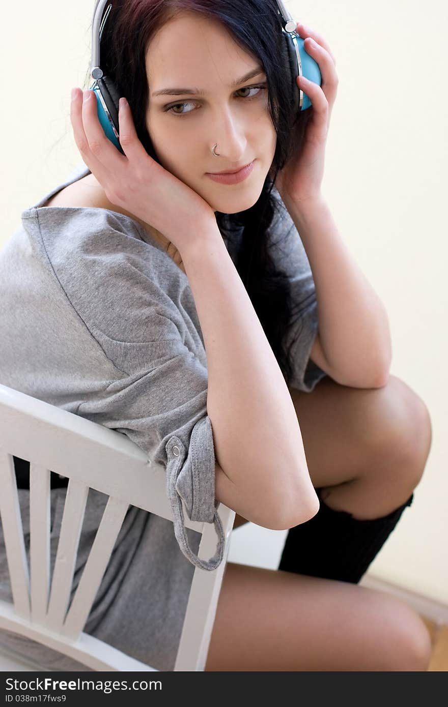 Caucasian dark haired woman with earphones on the chair