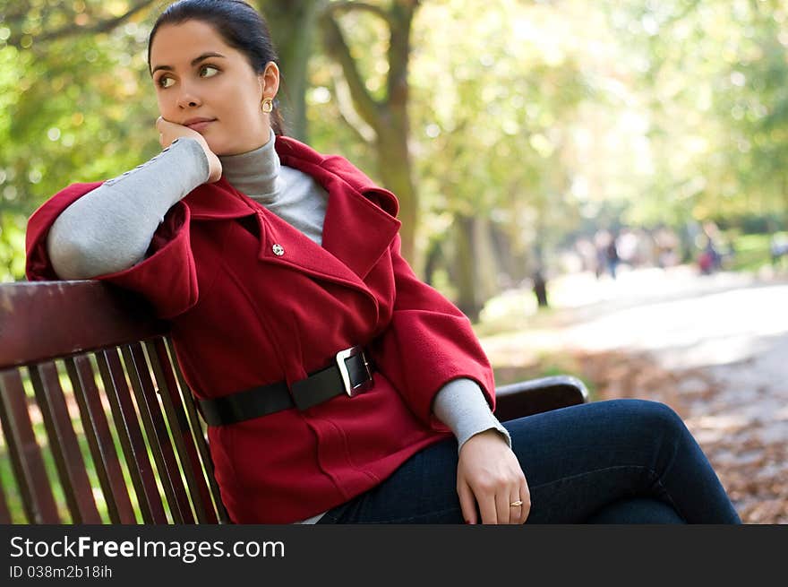 Woman sitting in a park on a wooden bench