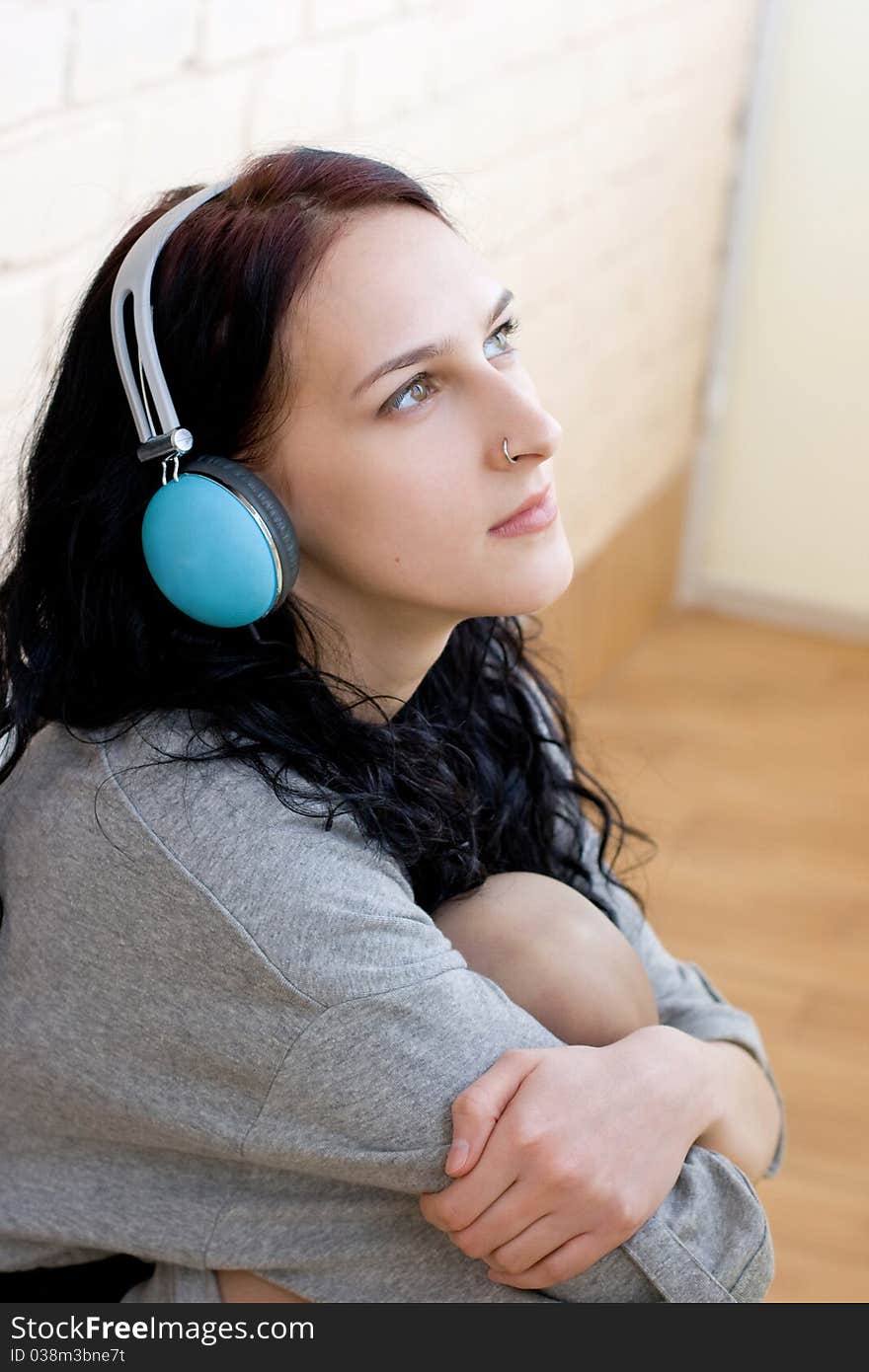 Caucasian dark haired woman with earphones on the chair