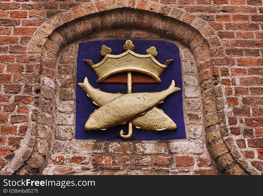 Close-up on an old brick wall decorated with two crossed fish under a crown, on blue background. Close-up on an old brick wall decorated with two crossed fish under a crown, on blue background.