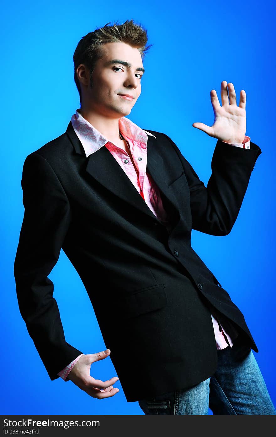 Young man dressed in rock'n'roll style, dancing over blue background. Young man dressed in rock'n'roll style, dancing over blue background.