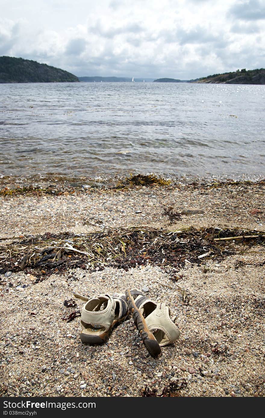 This is a shot of one pair of sandals on the beach. Focus on sandals. background soft focus.