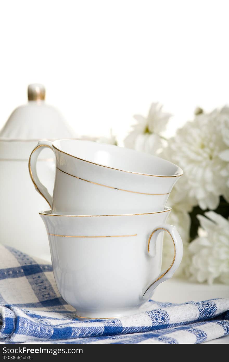 Two teacup on white-blue napkin on table against flowers