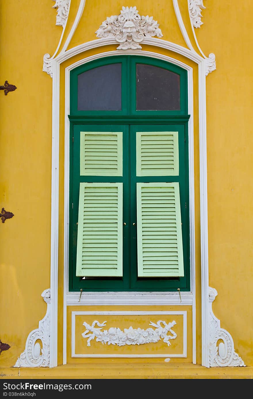 The closed green window on the yellow wall