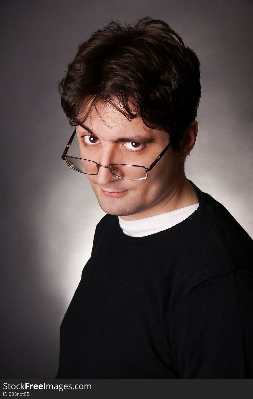 Portrait of young attractive dark-haired smiling grimacing man in eyeglasses, studio shot