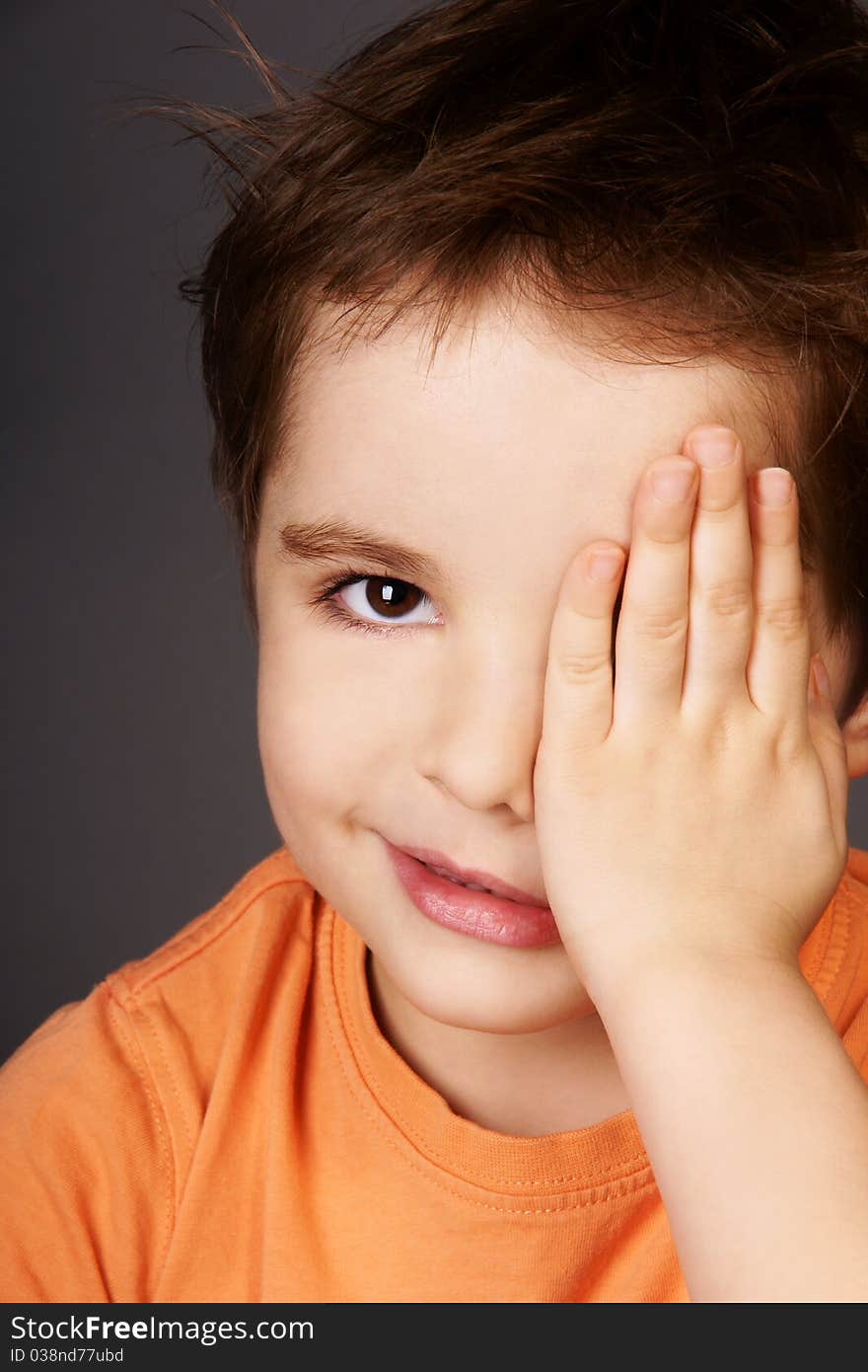 Portrait of cute smiling little boy closed one eye with his hand, studio shot. Portrait of cute smiling little boy closed one eye with his hand, studio shot