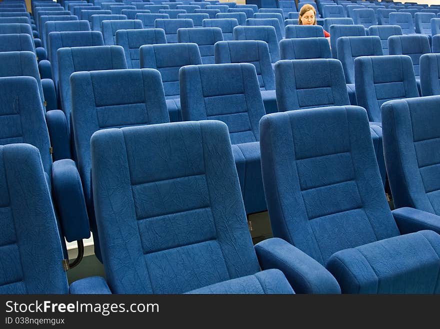 A womwn is sitting alone in an empty theater