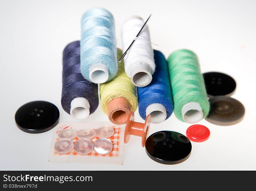 Thread sewing and needles with buttons on a white background