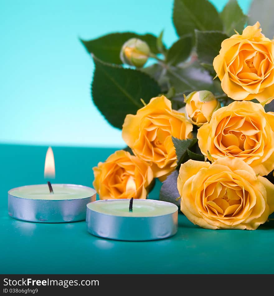 Beautiful yellow roses and candles on a green background