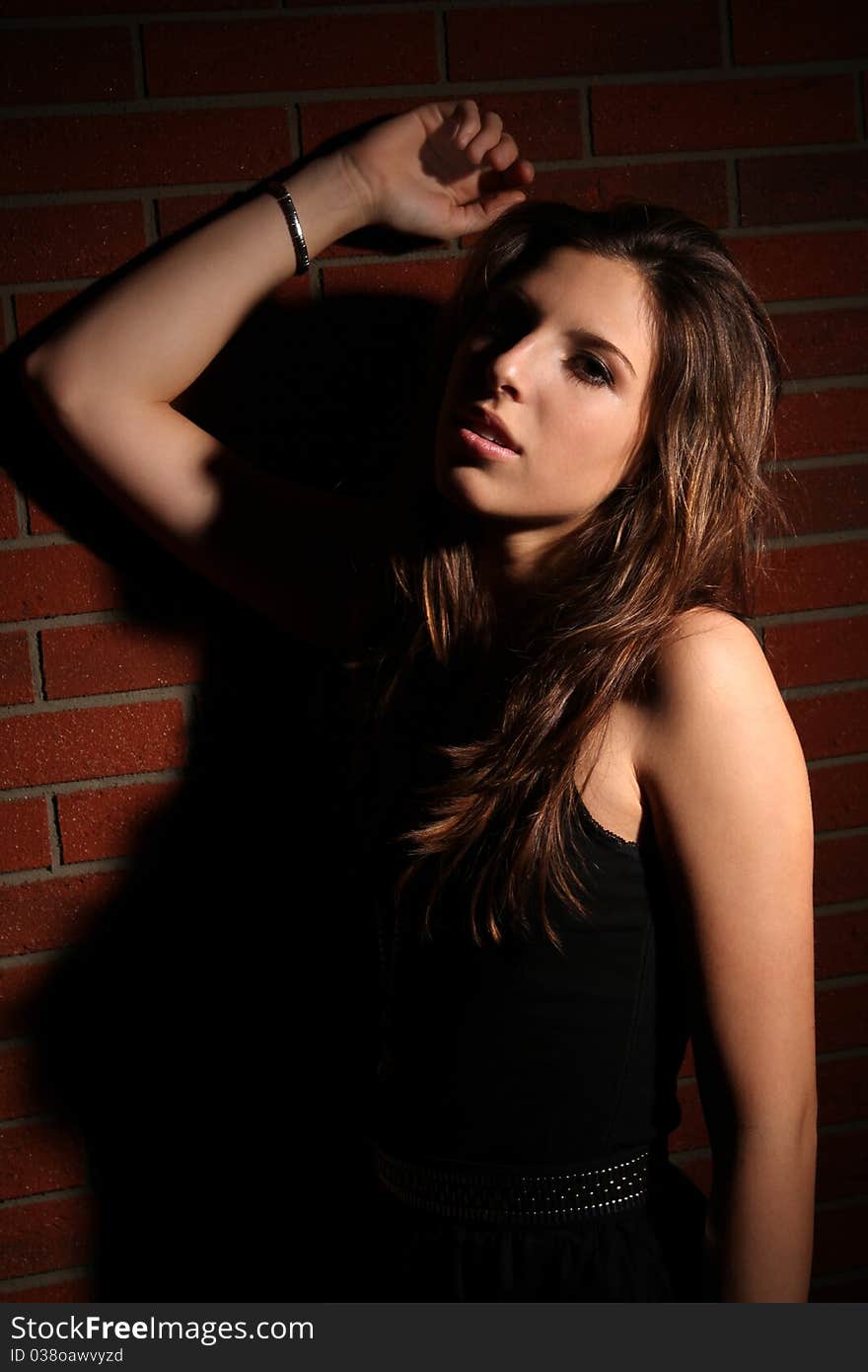 Beautiful brunette girl wearing a black dress posing on a brick stone wall. Beautiful brunette girl wearing a black dress posing on a brick stone wall