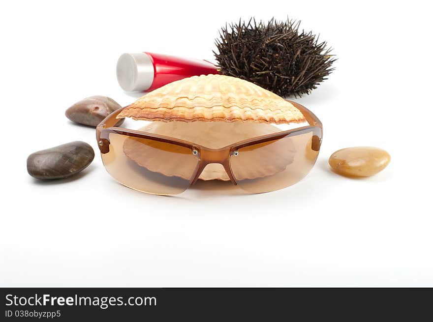 Sun glass on white background with seashell,stones, sea-urchin and sun block. Sun glass on white background with seashell,stones, sea-urchin and sun block