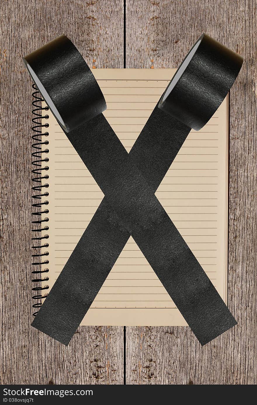 Vintage notebook stuck by black tape with wood background