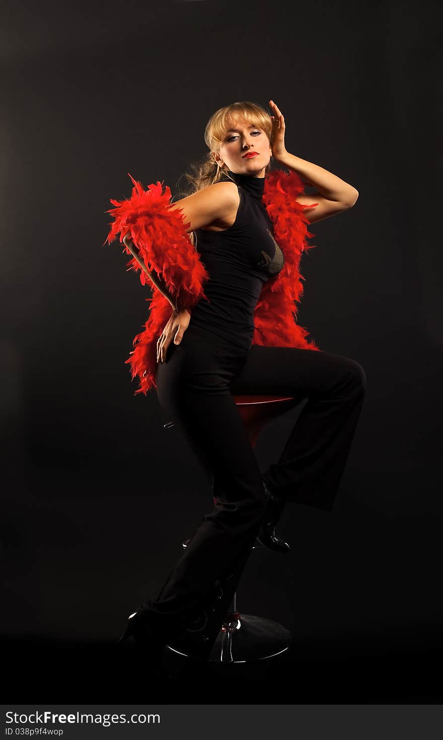 Blond woman dance with red boa in dark