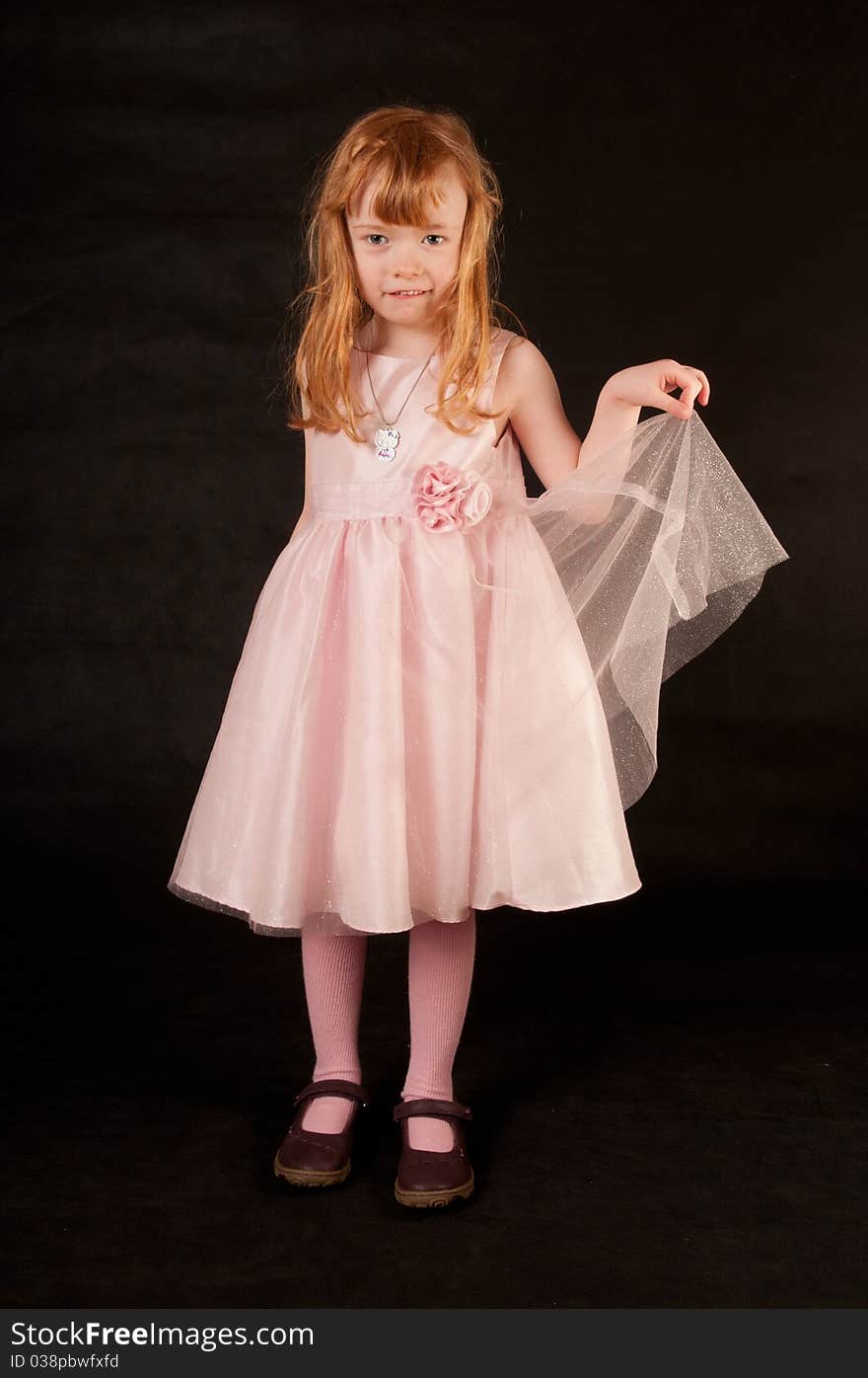 Cute little girl in pink dress against black background