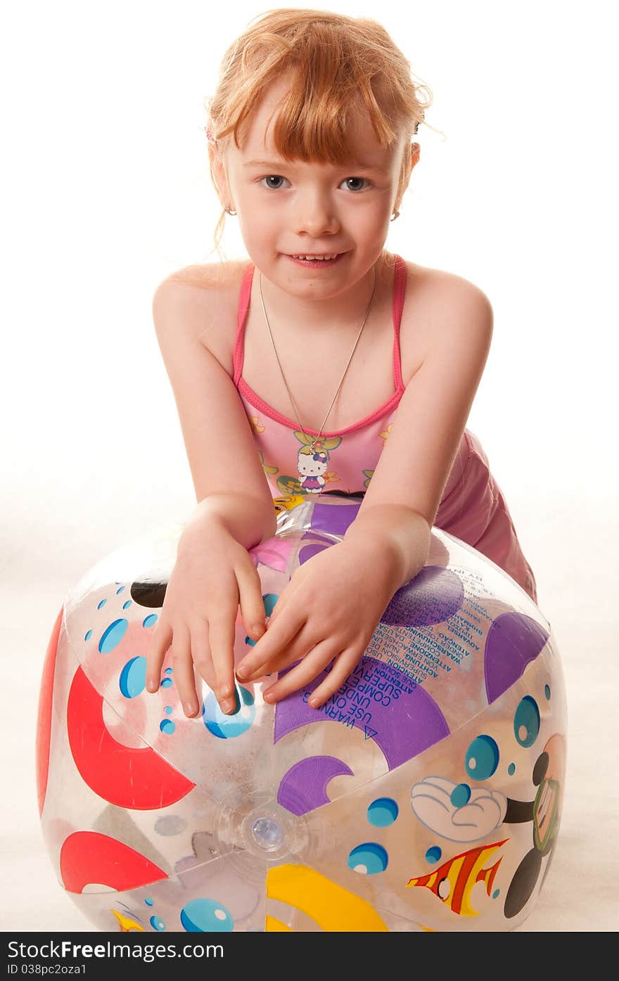 Cute little girl in pink swimsuit playing with a beach ball