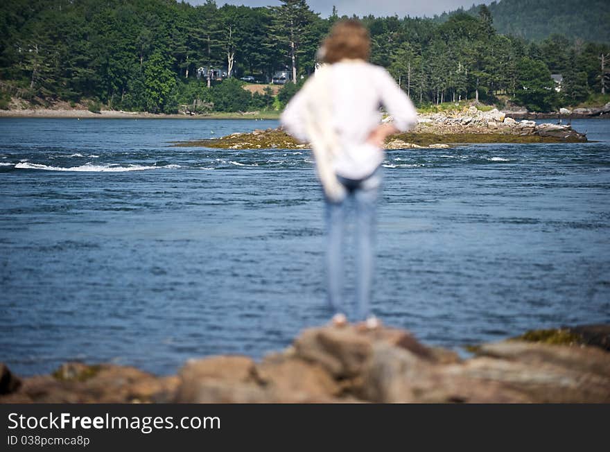 A woman looks out onto a cove in Down East Maine. A woman looks out onto a cove in Down East Maine.