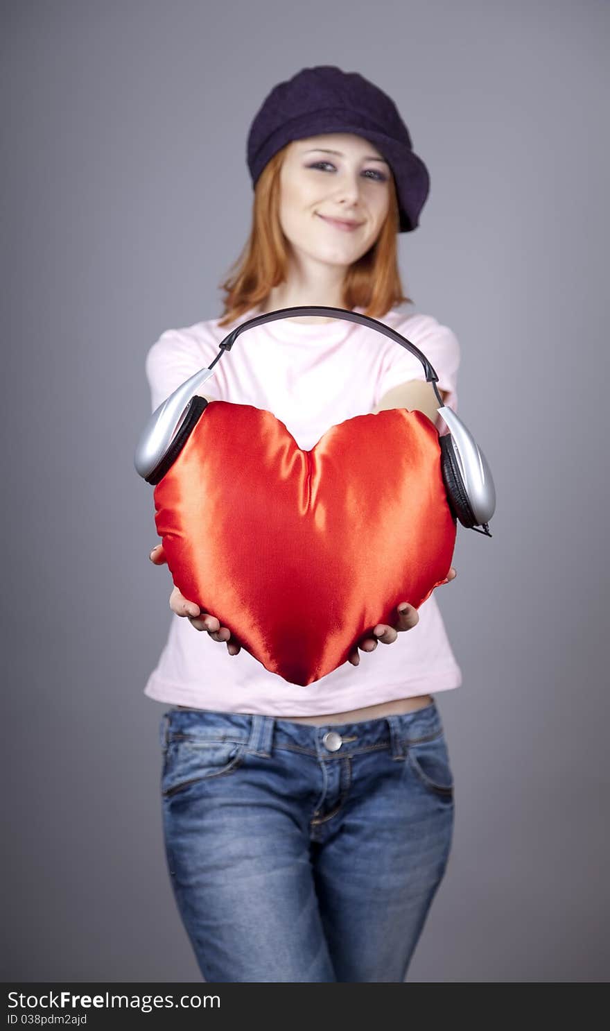 Beautiful red-haired girl with toy heart. Studio shot.