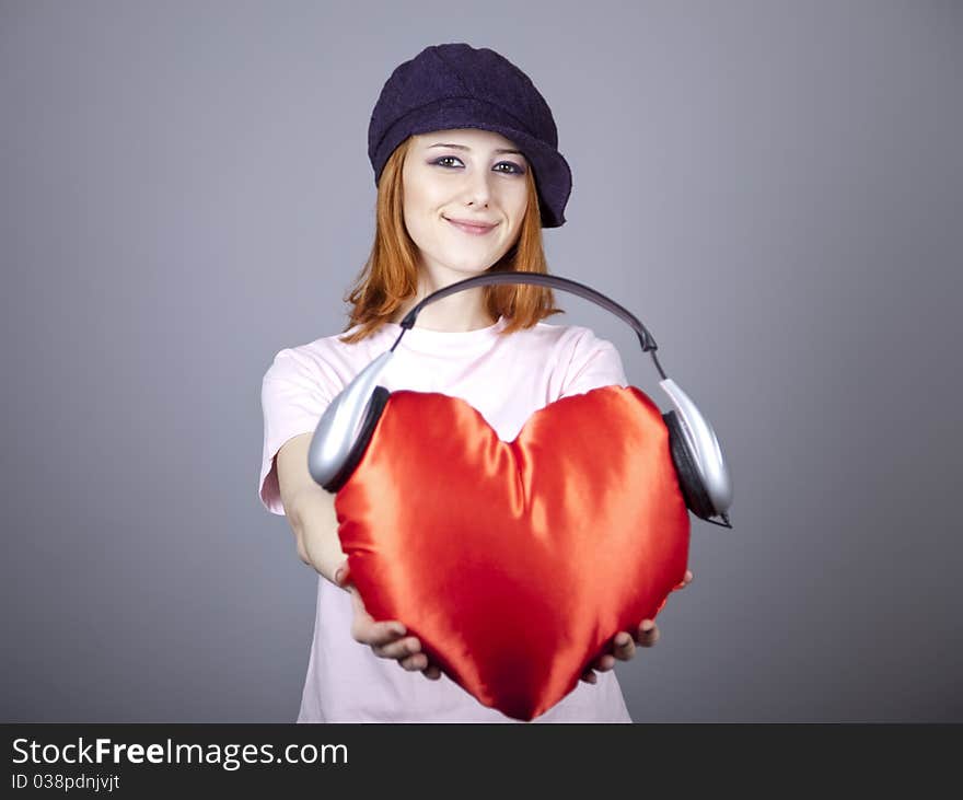 Beautiful red-haired girl with toy heart. Studio shot.