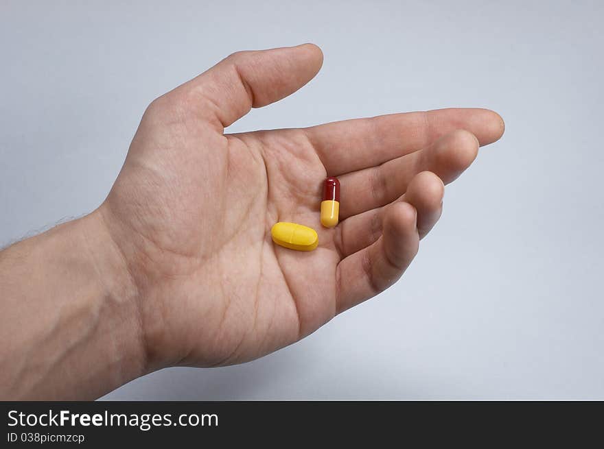 Hand with two pills, blue background