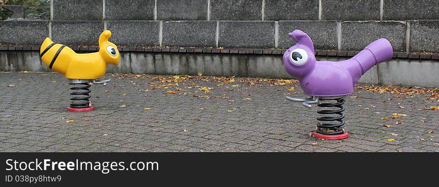 Playground for children with two plastic animals on springs by rainy autumn day