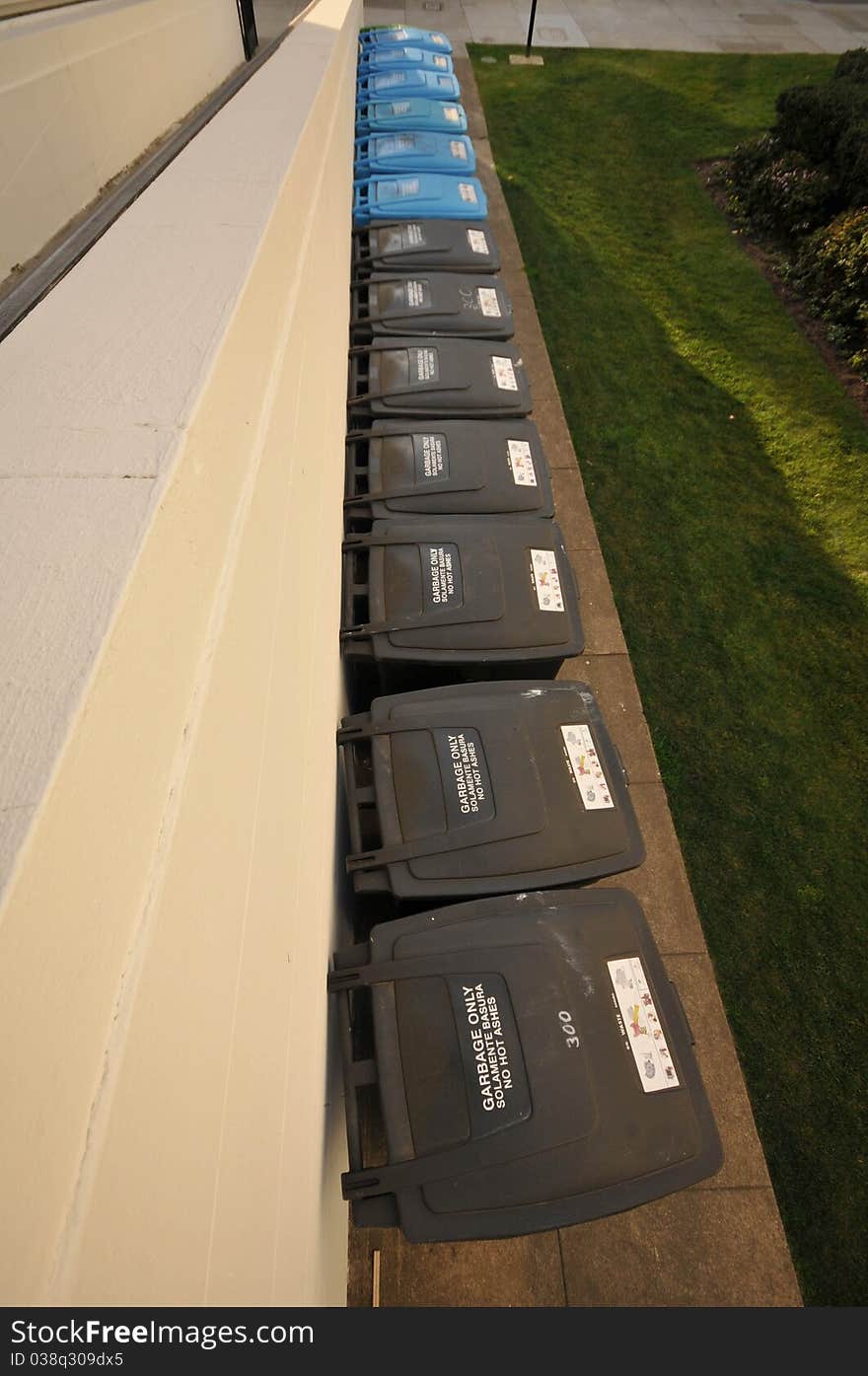 A row of recycling and garbage cans from above. A row of recycling and garbage cans from above.