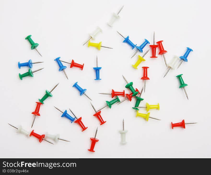 Colored push pins from above on a white background