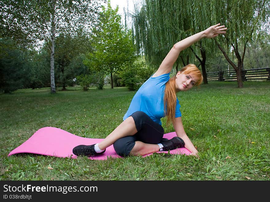 Young woman engages in fitness on beautiful lawn in a birchwood