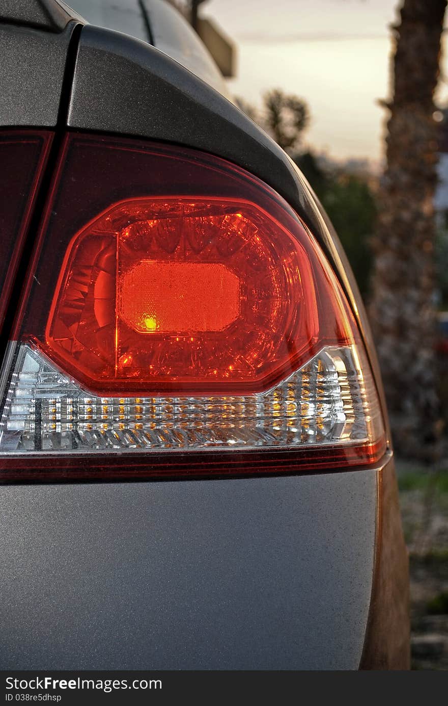 Close up of car tail lights with palm trees in the horizon