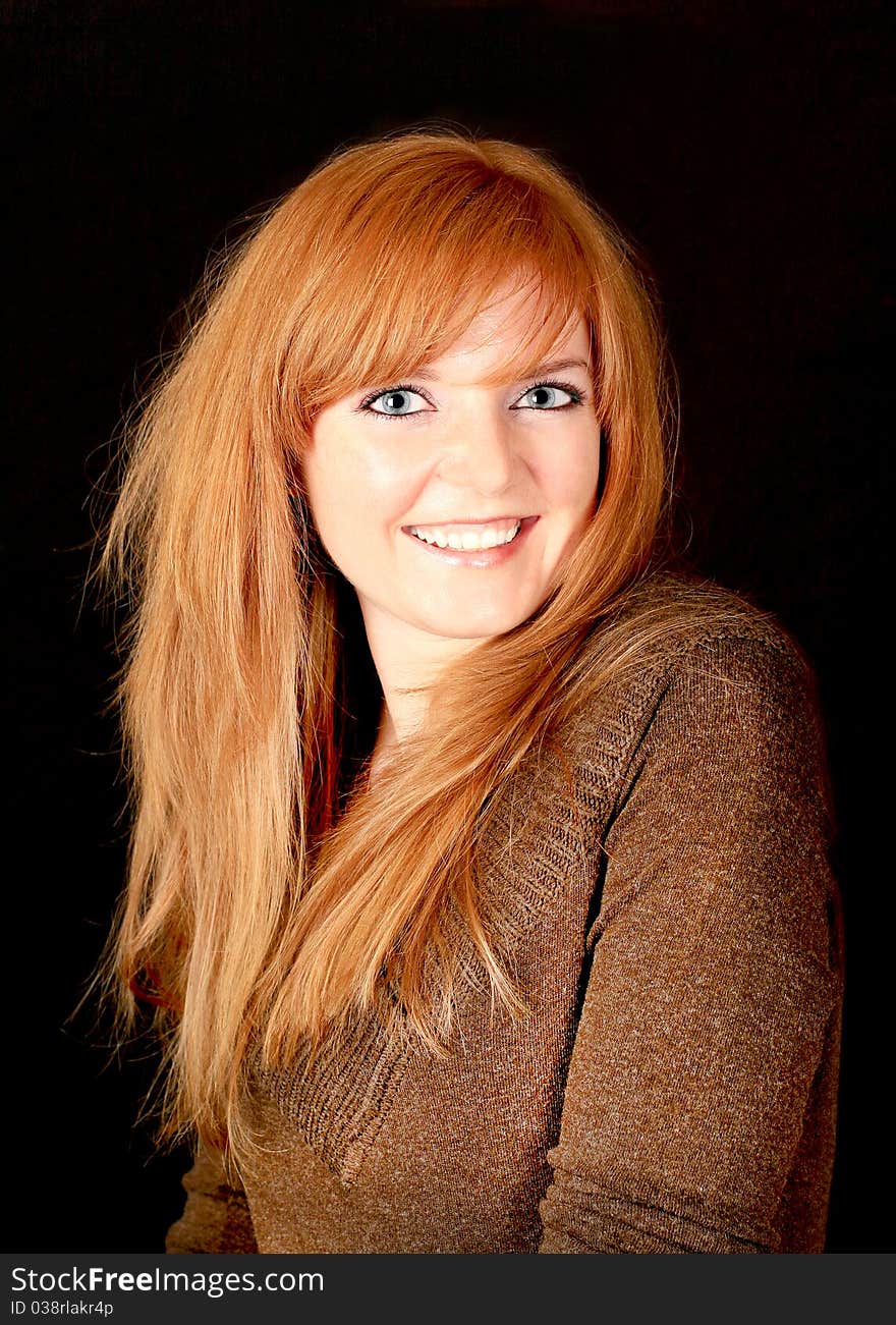 Young red-haired girl smiling on a dark background