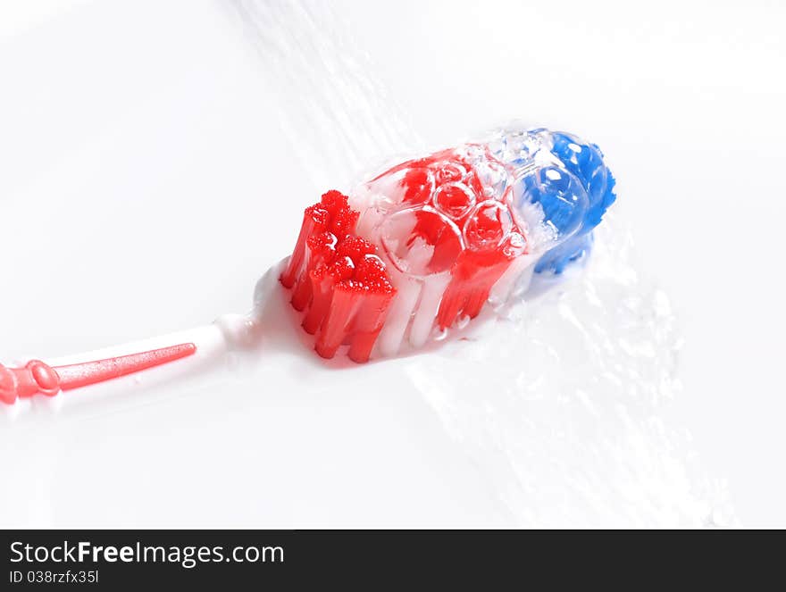 Water pouring on red, white and blue wet toothbrush