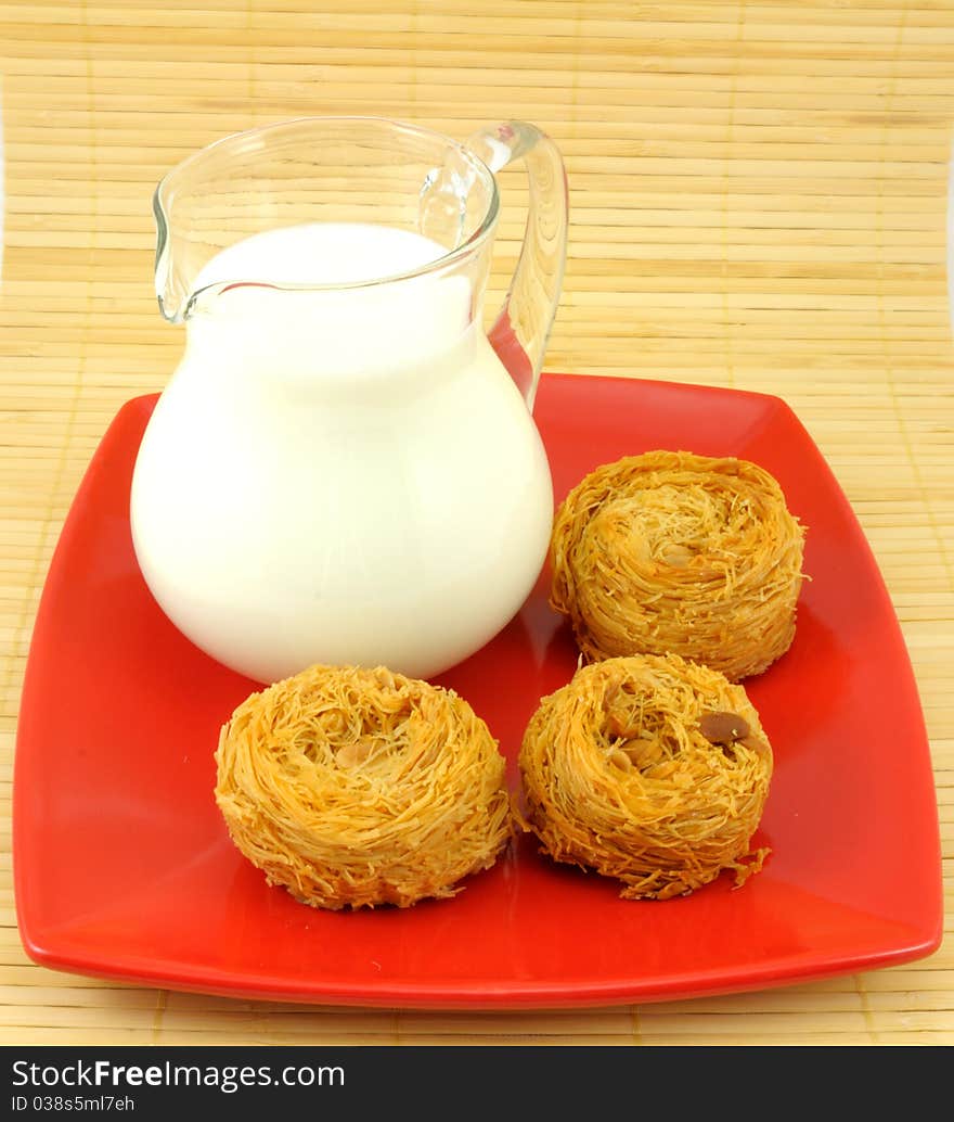 Milk jug and cake on red plate