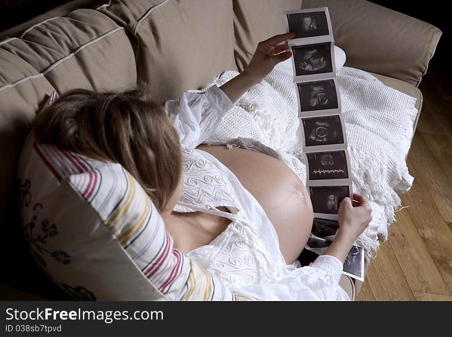 Happy beautiful pregnant woman relaxing on sofa with echo in hands