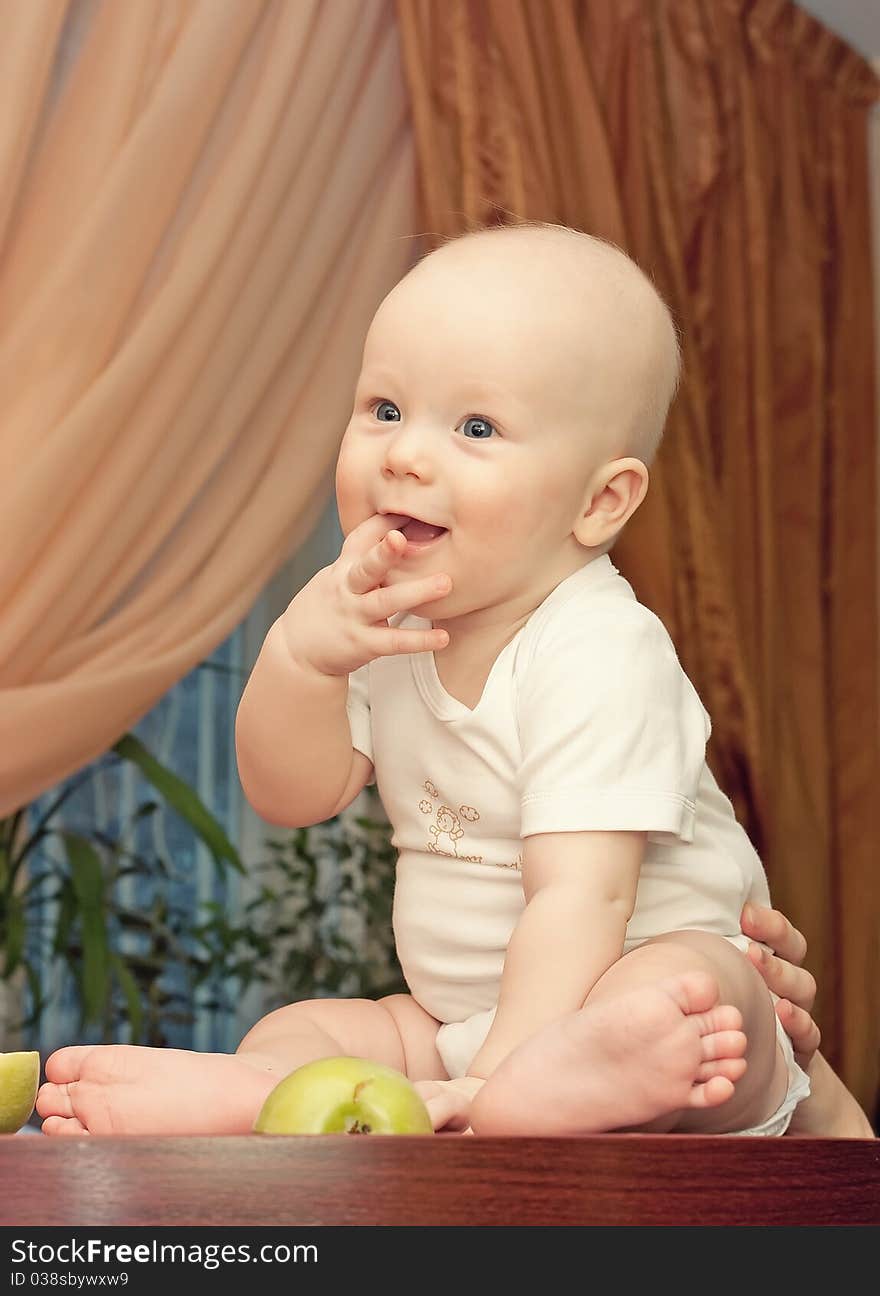 A cute little baby sitting on the table. A cute little baby sitting on the table