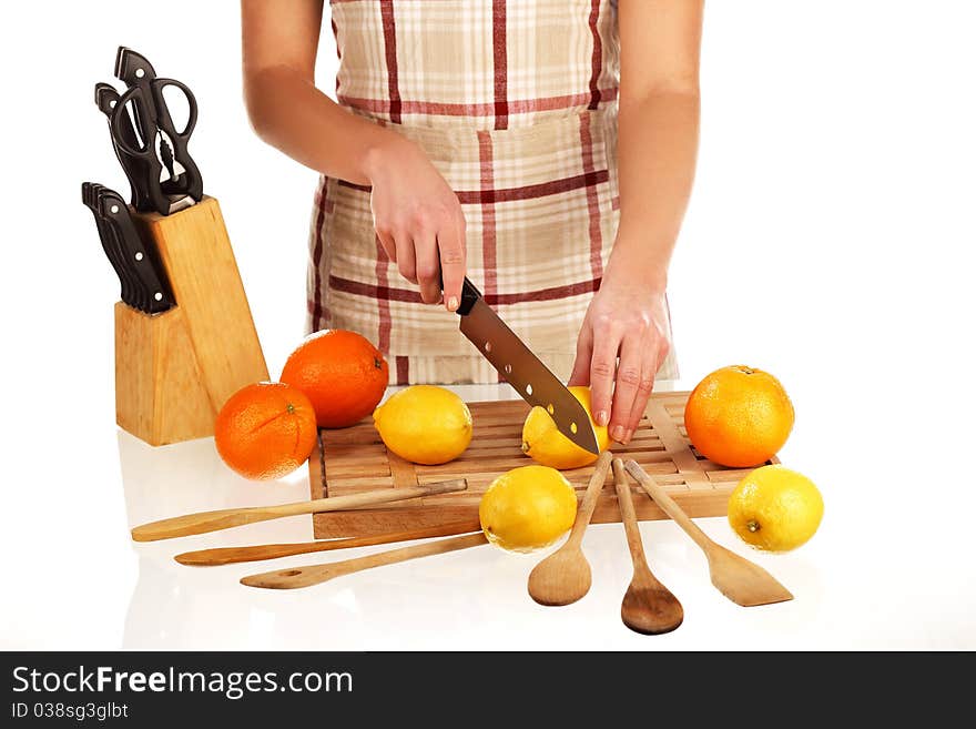 Girl cutting lemons with the knife, on a wooden plate. Girl cutting lemons with the knife, on a wooden plate