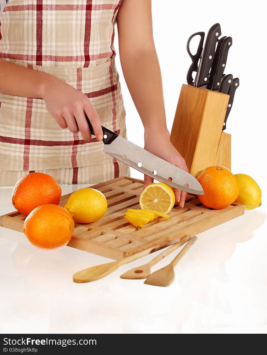 Girl cutting lemons with the knife, on a wooden plate